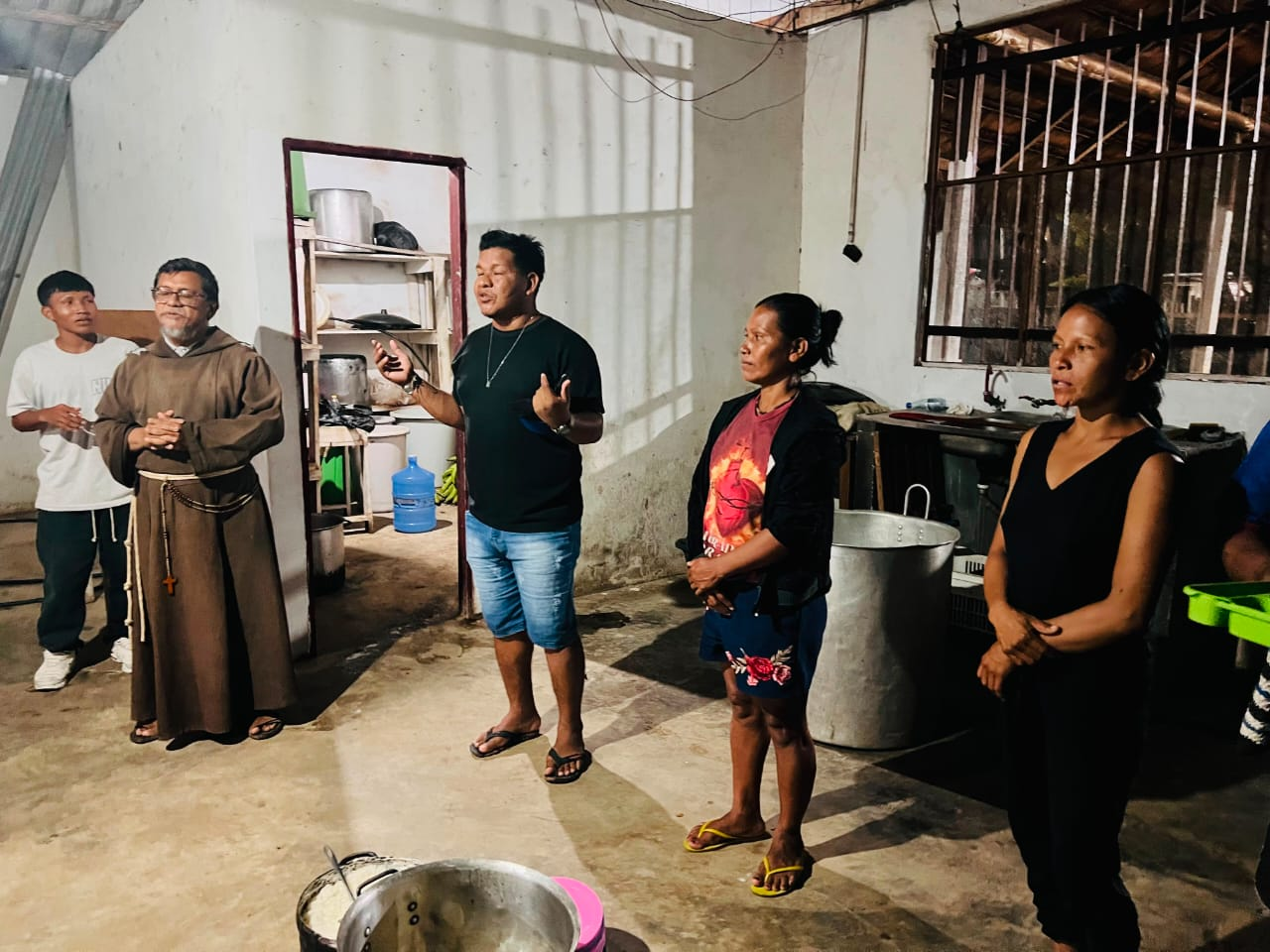 Momento de oração antes da refeição com frade e comunidade