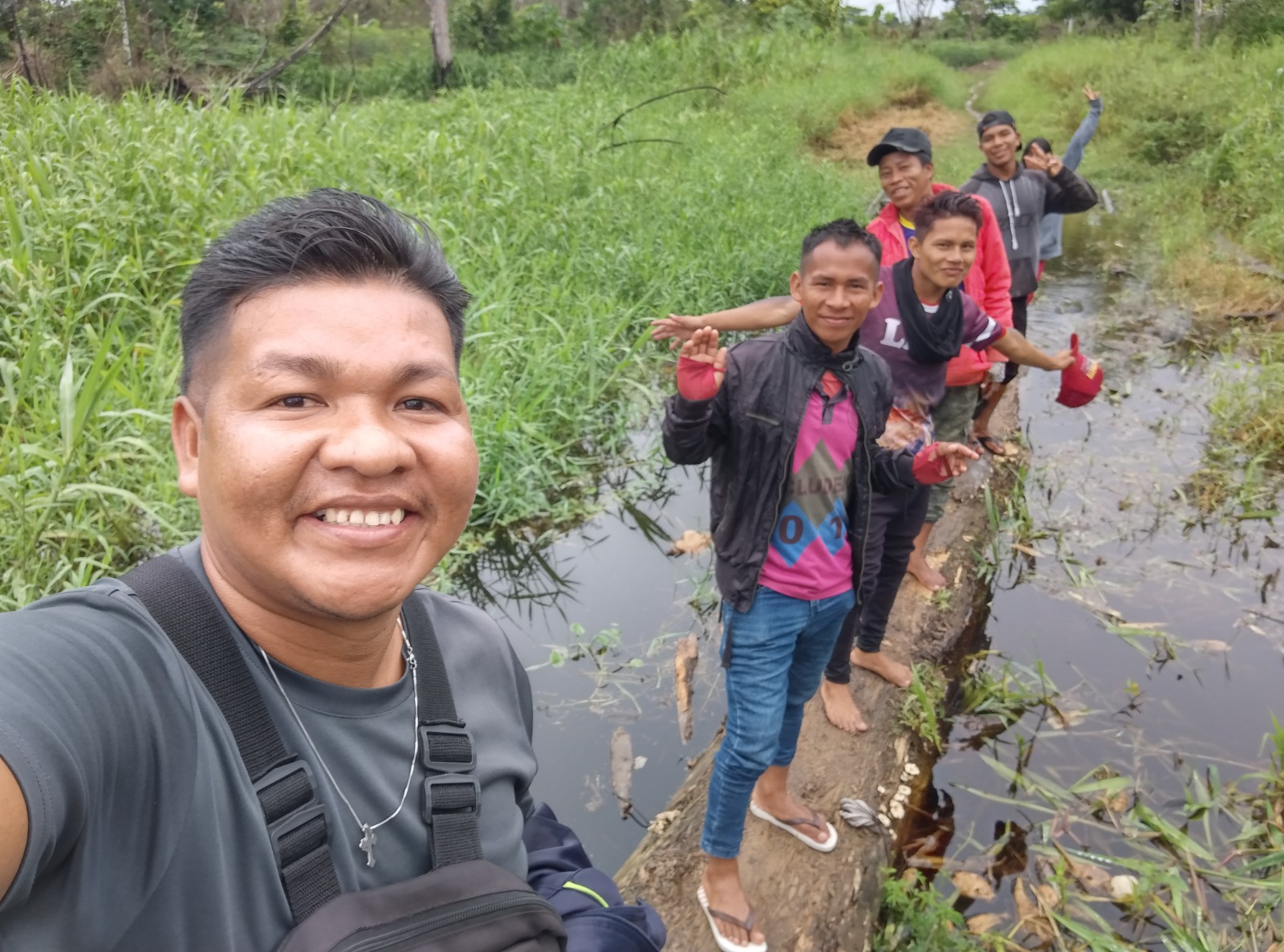 Jovens atravessando um tronco na floresta amazônica