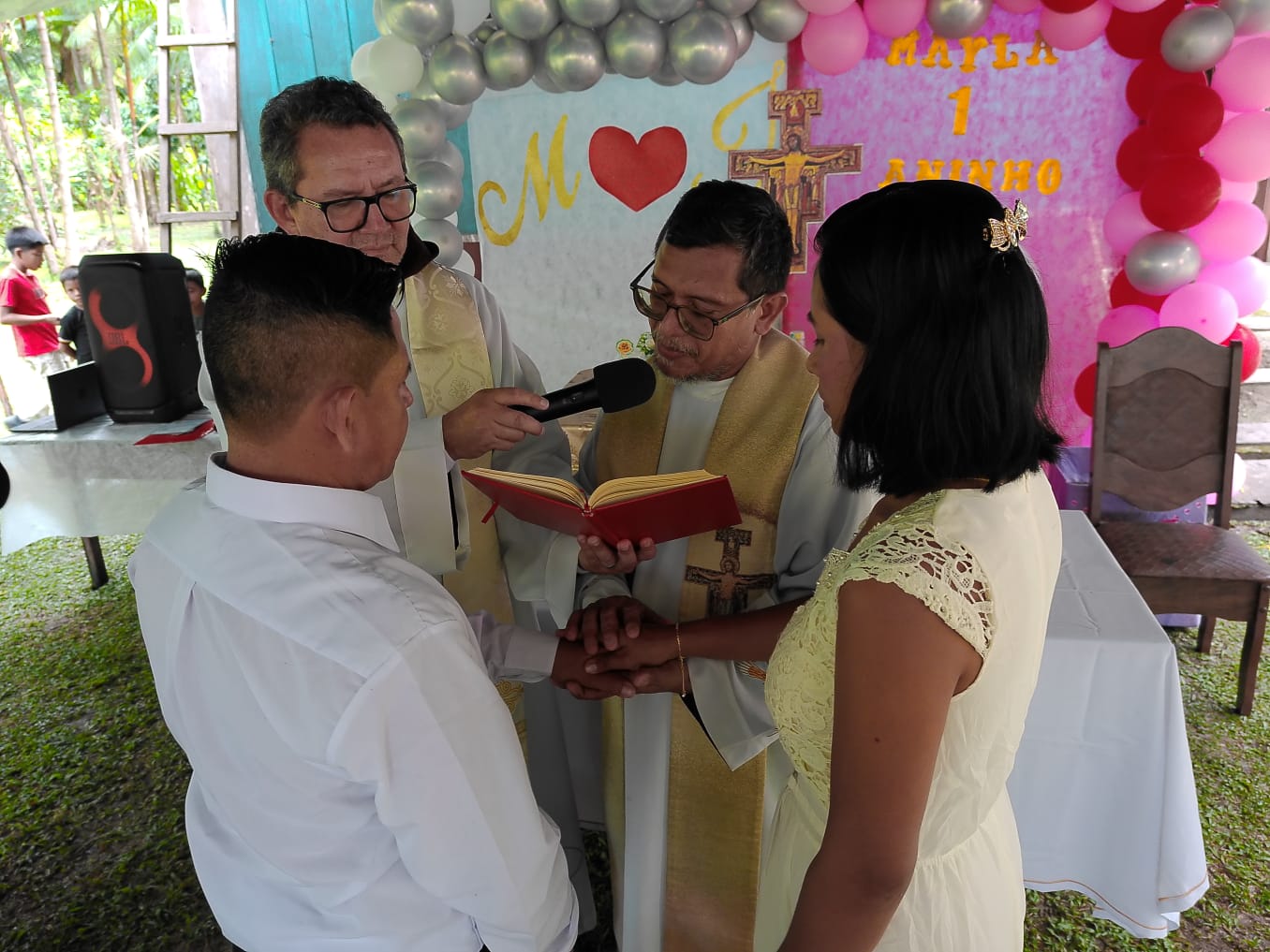 Frades celebrando casamento na comunidade com os noivos de mãos dadas