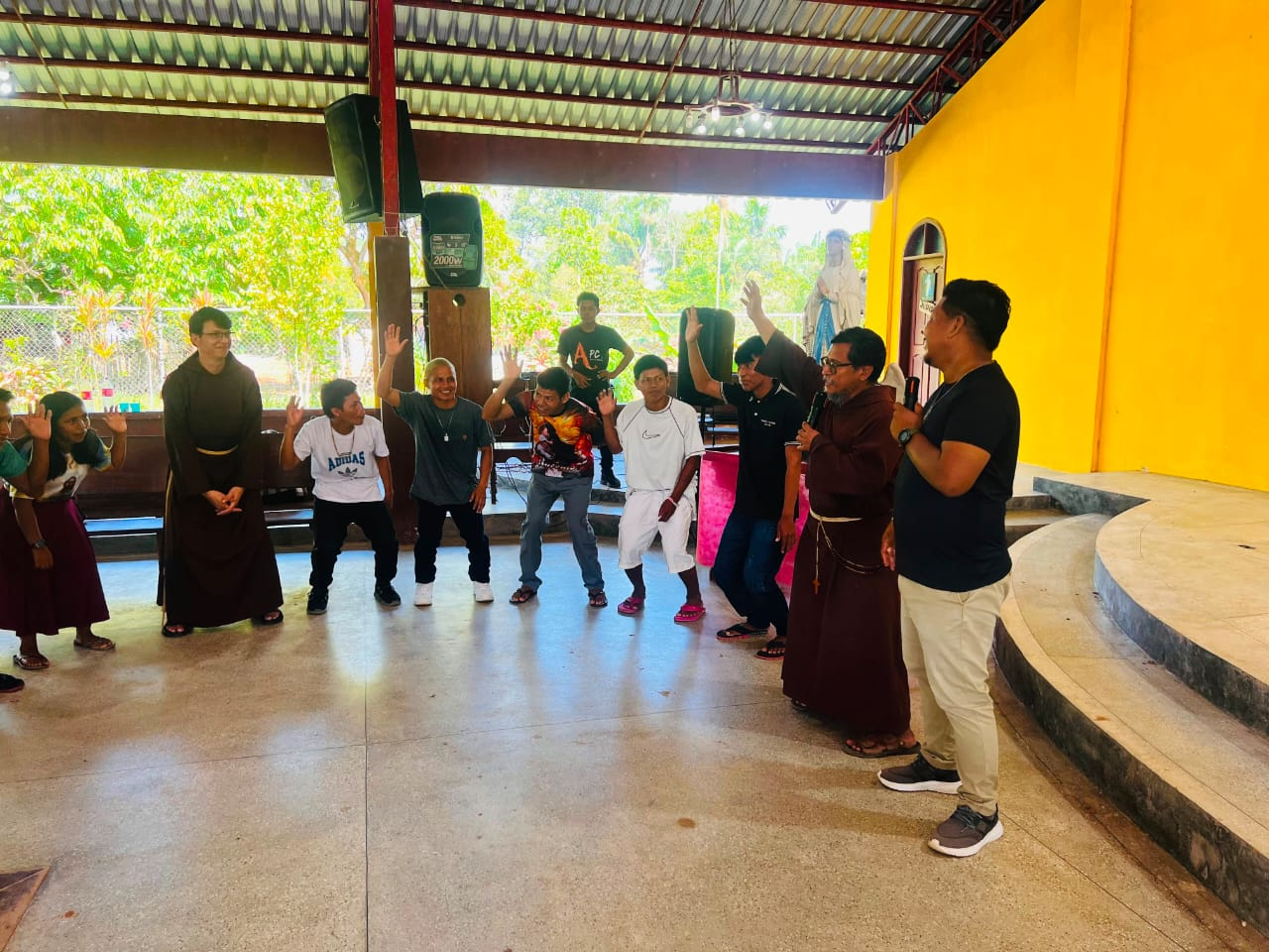 Dinâmica animada com frades e jovens no salão comunitário