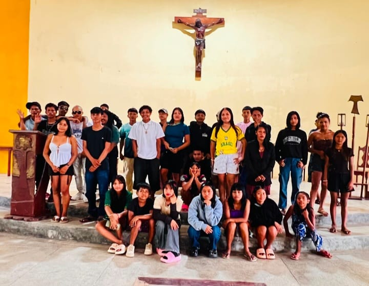 Grupo de jovens posando para foto na capela, em frente ao crucifixo.