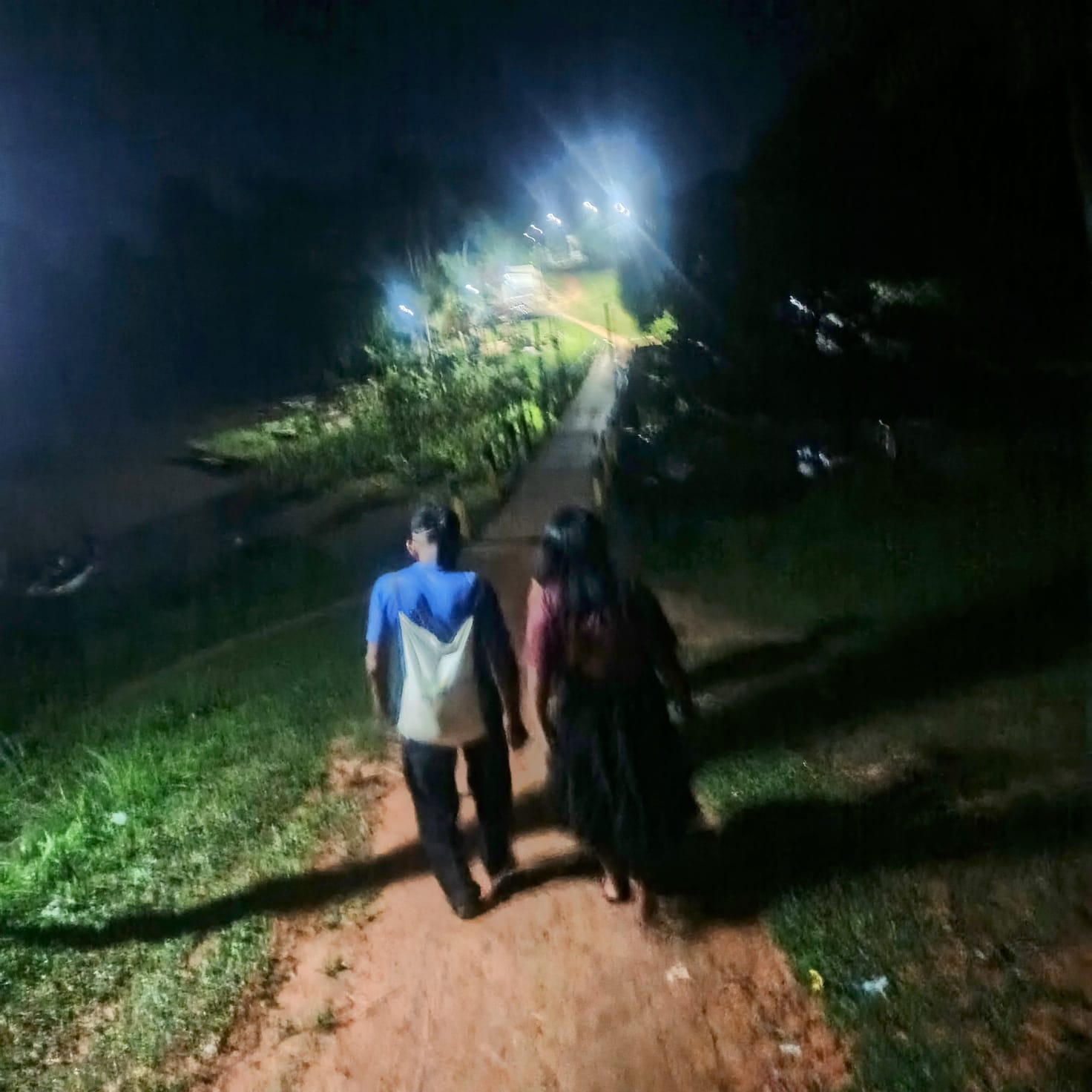 Frade caminhando à noite com moradora por estrada da comunidade