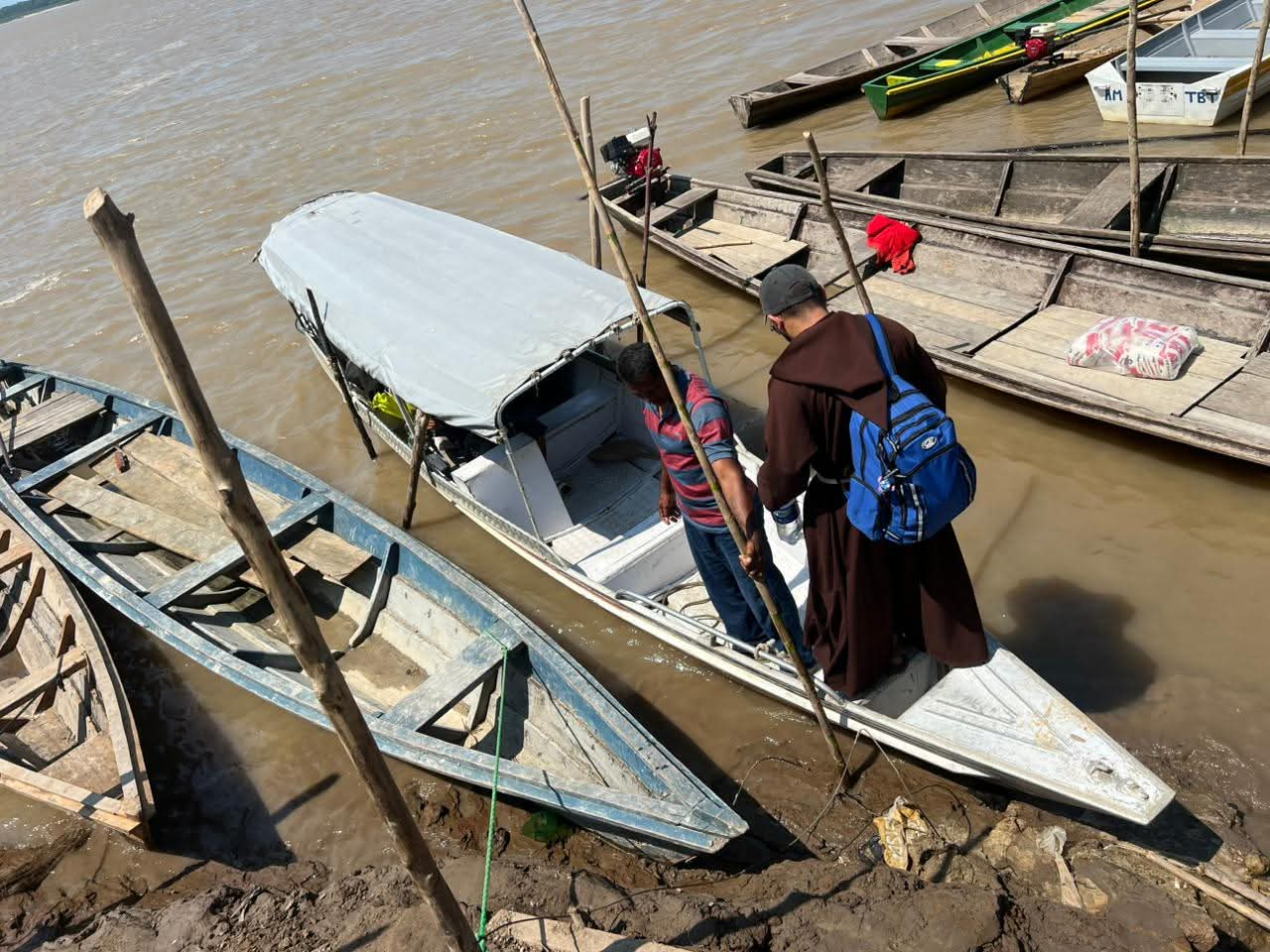 Frade embarcando em pequena lancha às margens do rio